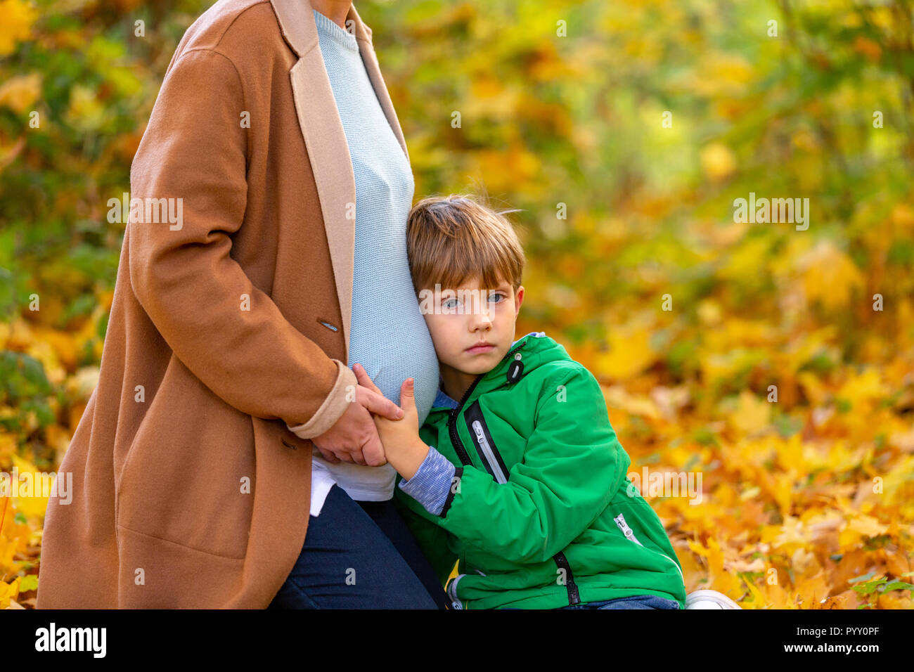 Cute sweet Caucasian child listening to his pregnant mother's belly
