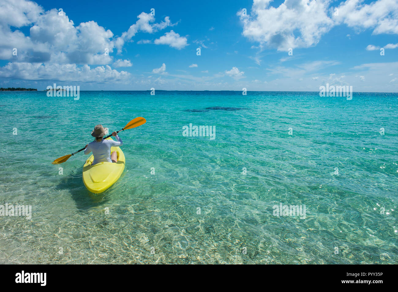 Female tourist kayaking in the turquoise waters of Tikehau, Tuamotu Archipelago, French Polynesia Stock Photo