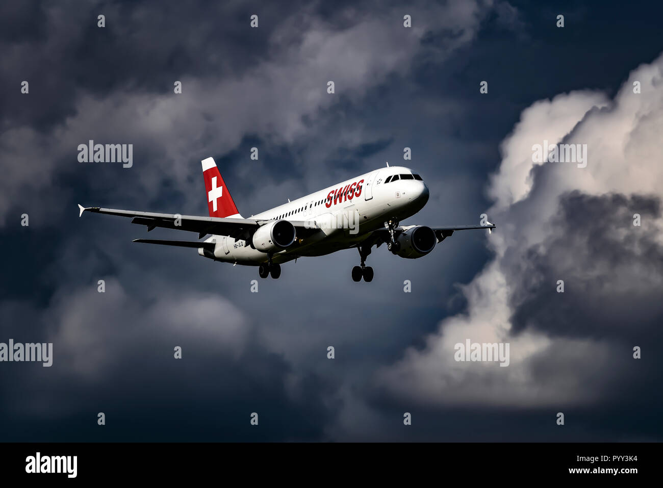 Swiss Airbus A320, in flight in front of dark cloudy sky, Switzerland Stock Photo