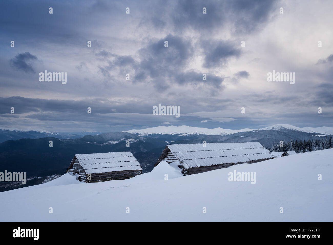 Mountain huts in the snow. Winter landscape with a stormy sky. Severe weather Stock Photo