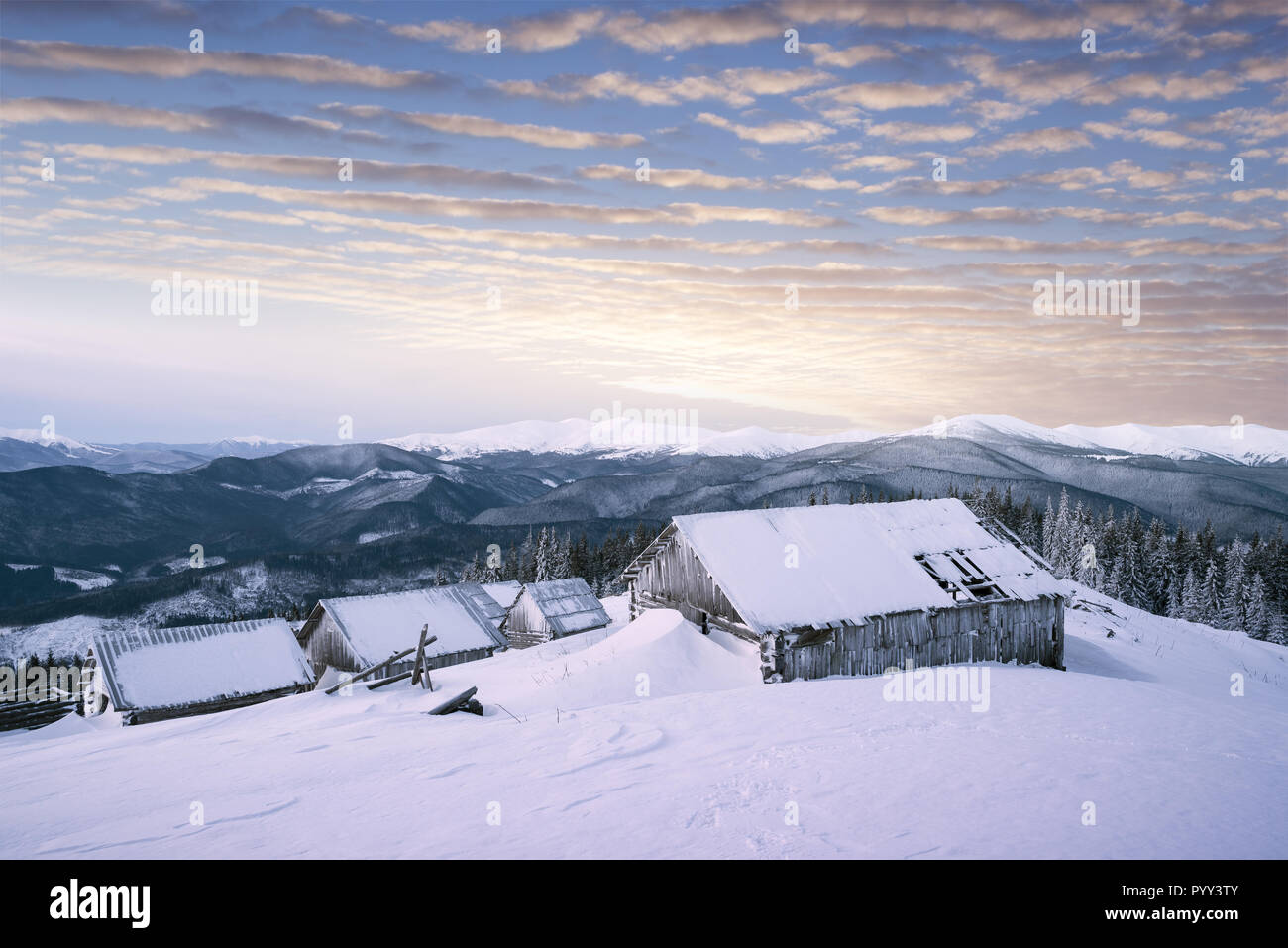 Winter sunrise in the mountains. Old wooden huts in the snow Stock Photo