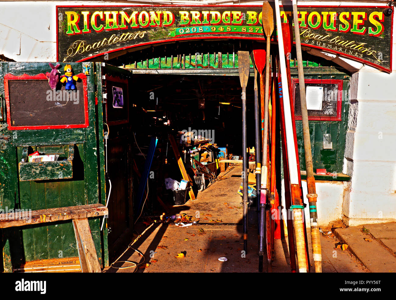 An image depicting one of the colourful boat workshops next to Richmond Bridge which straddles the River Thames, in London. Stock Photo