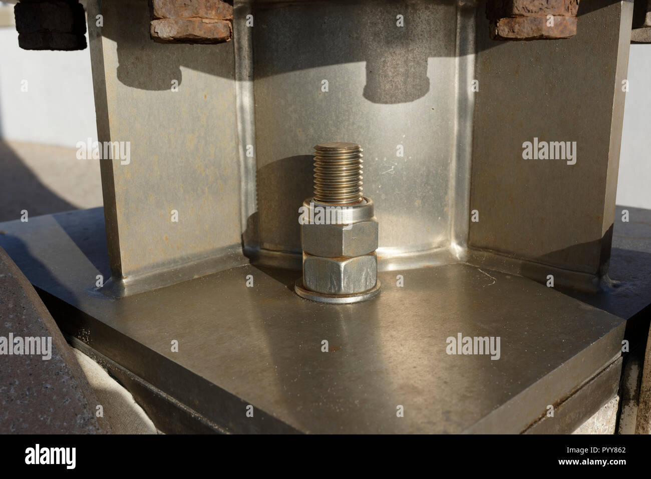 Stainless steel anchor bolt and nuts securing fabricated and welded