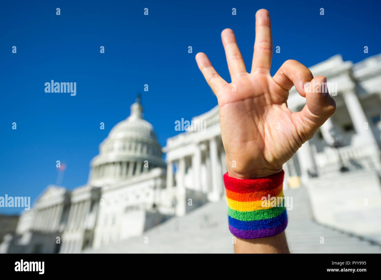 Gay OK hand wearing a rainbow pride wristband gesturing in front of the Capitol Building in Washington, DC, USA Stock Photo