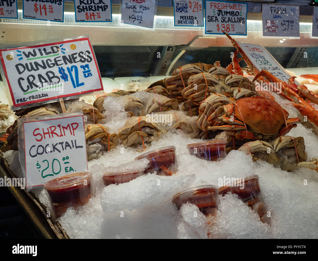 Dungeness crab and shrimp cocktails sitting in ice store front at a