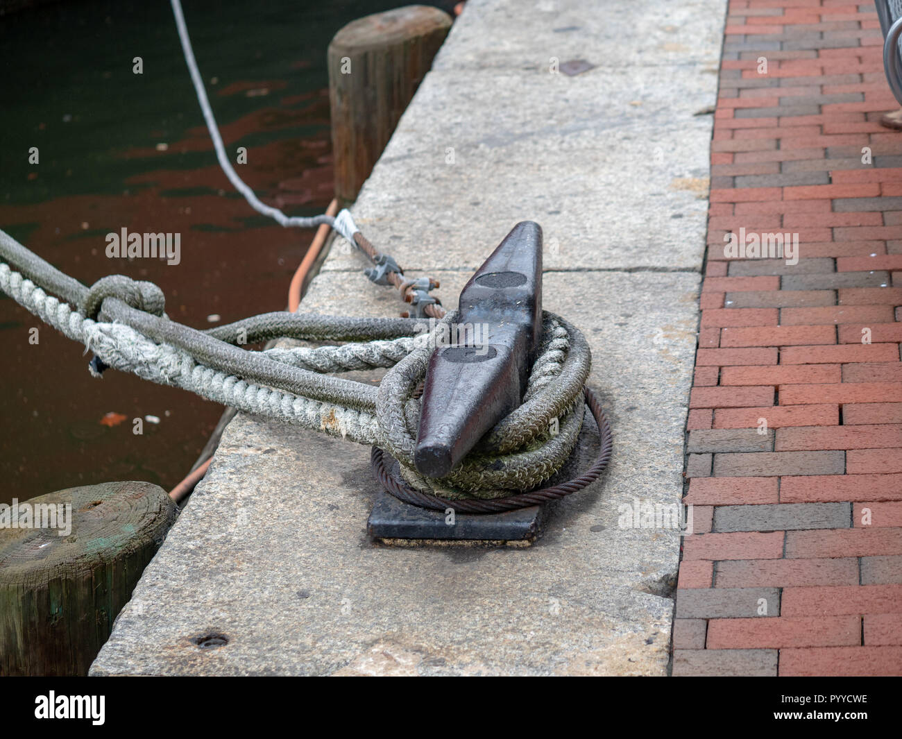 An anchor rope tied to a cleat securing a boat to the harbour