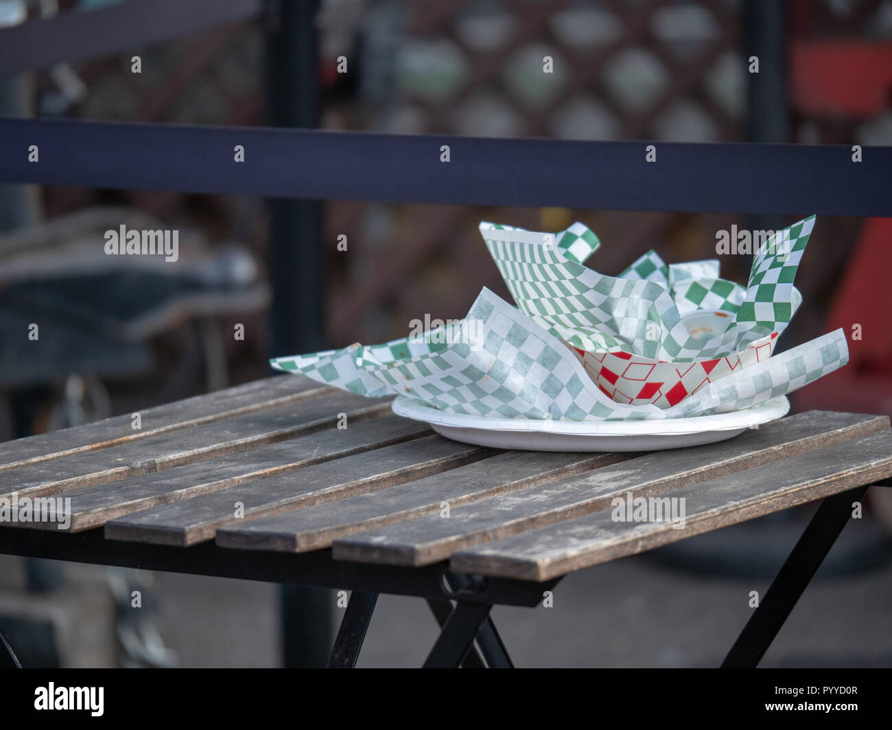 Paper plate with food truck and fast food wrappers and containers sitting on picnic table Stock Photo