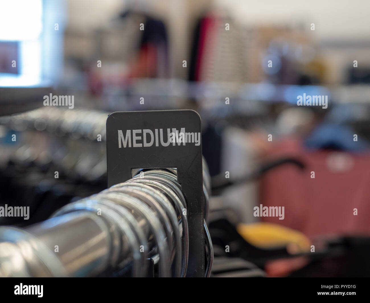 Medium section sign on steel clothing rack with hangers in department store Stock Photo