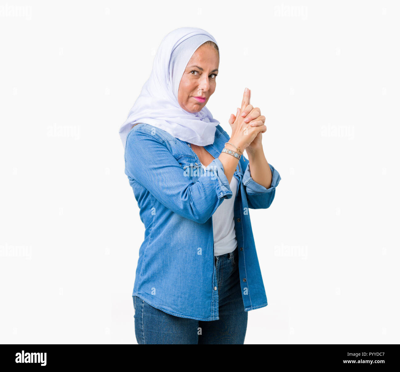 Middle age eastern arab woman wearing arabian hijab over isolated background Holding symbolic gun with hand gesture, playing killing shooting weapons, Stock Photo