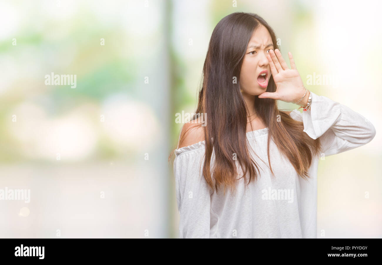 Young asian woman over isolated background shouting and screaming loud ...