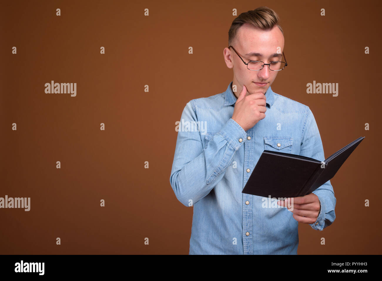 Portrait of young student man reading book and thinking Stock Photo