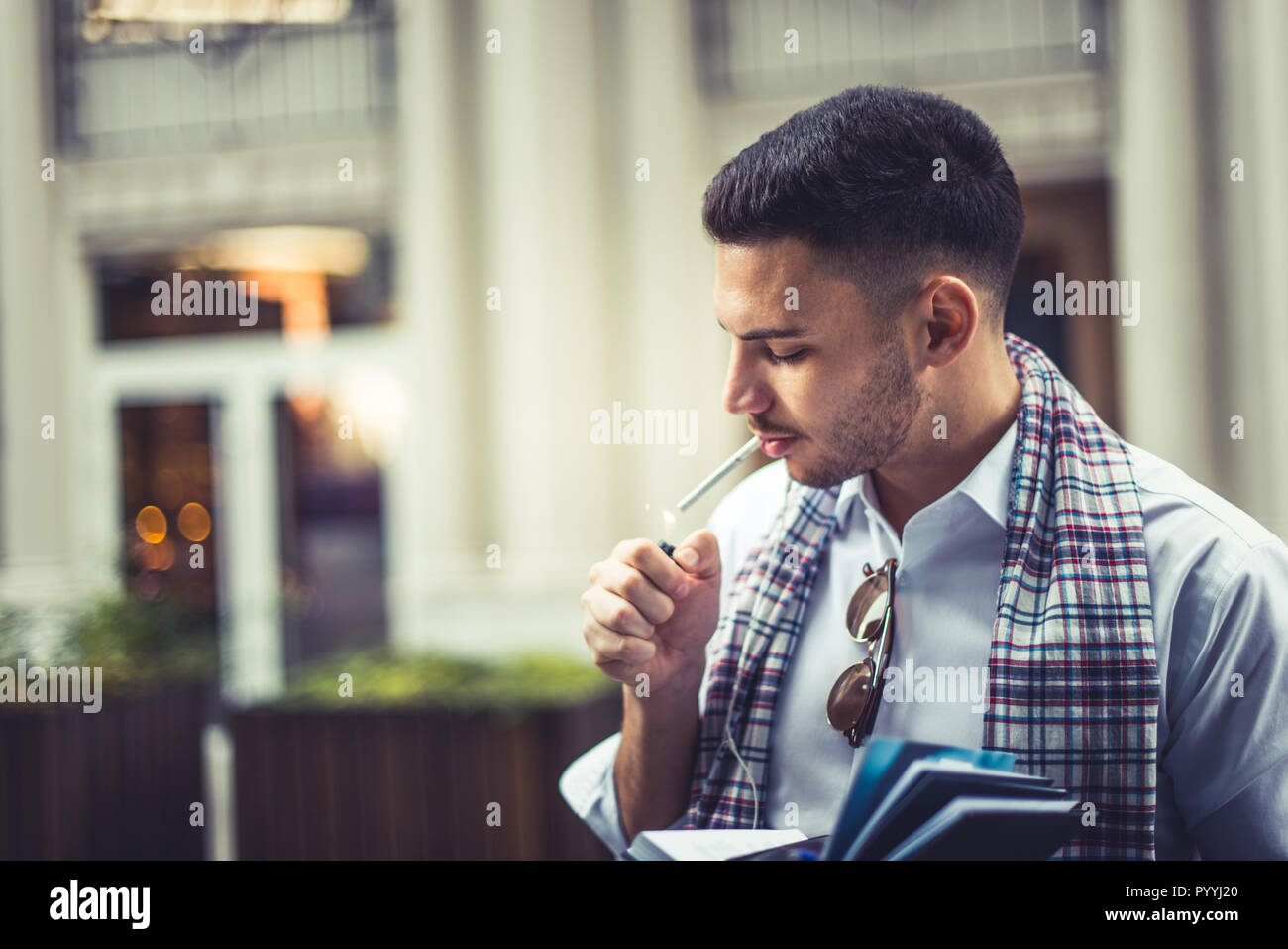 Stylish young businessman is lighting a cigarette in the city Stock