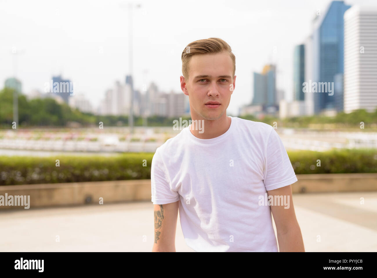 Young handsome man with blond hair relaxing at the park Stock Photo