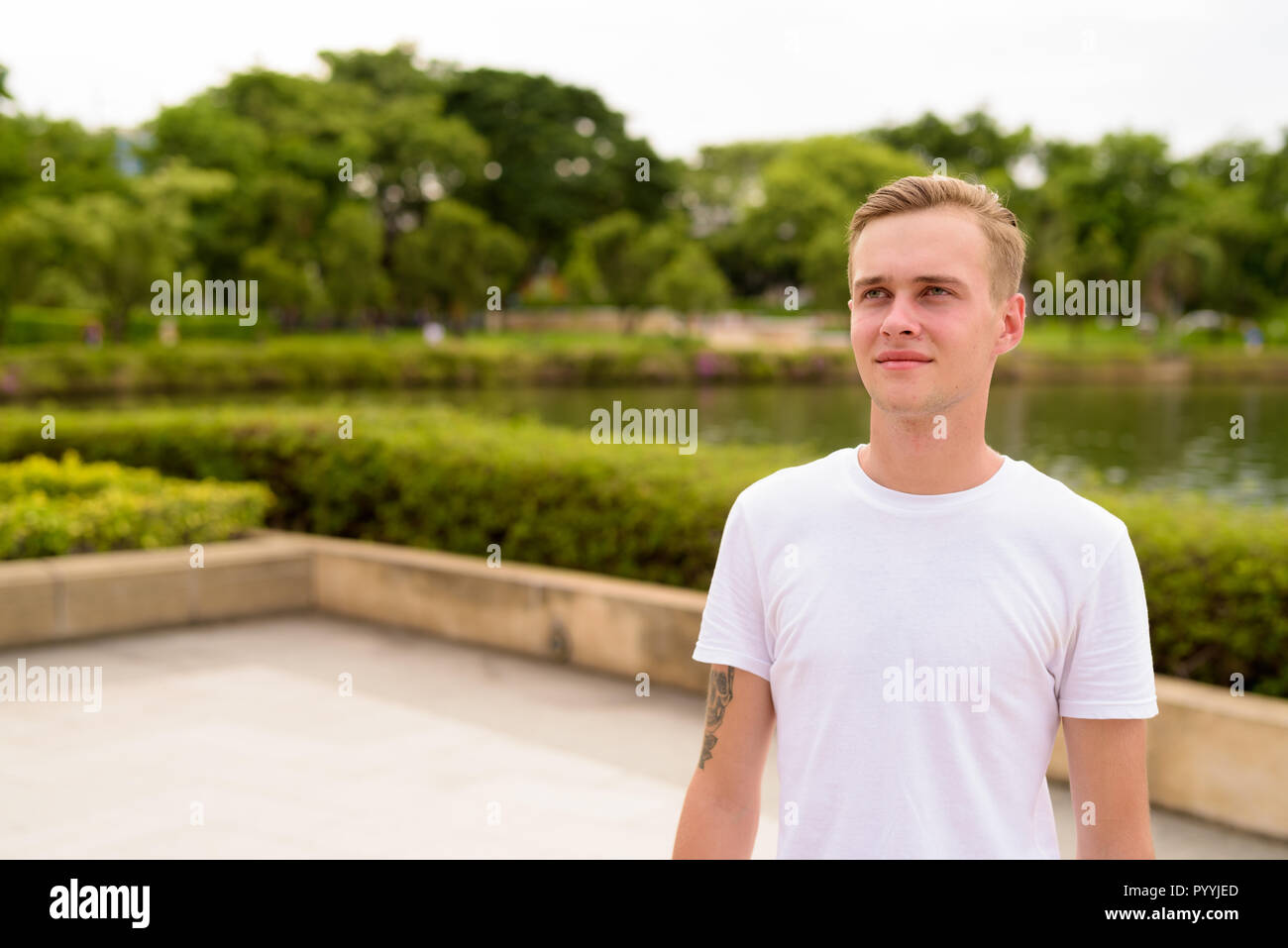 Young handsome man with blond hair relaxing at the park Stock Photo