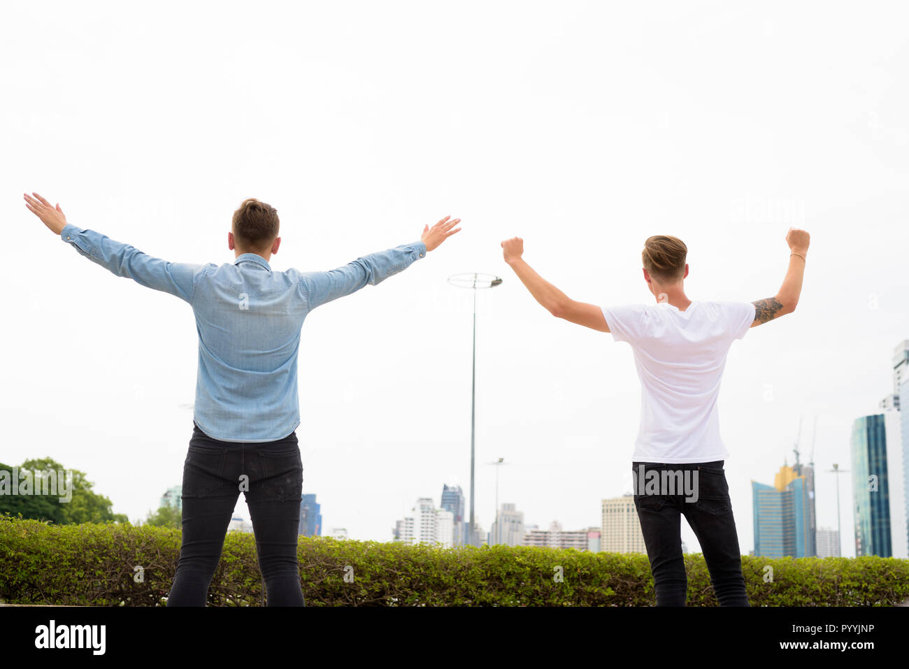 Two young man with arms raised outdoors Stock Photo