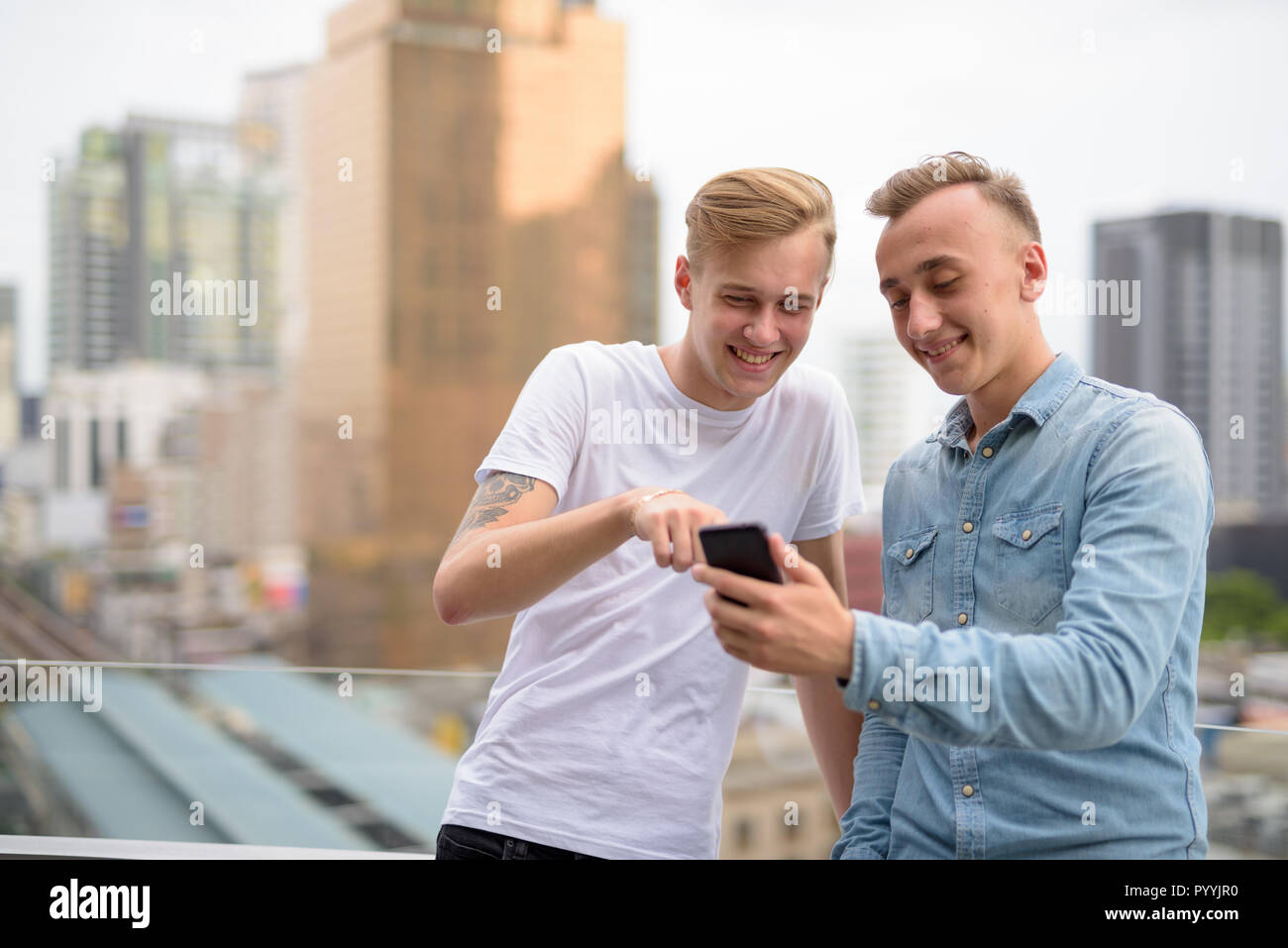 Young happy man couple using mobile phone outdoors Stock Photo