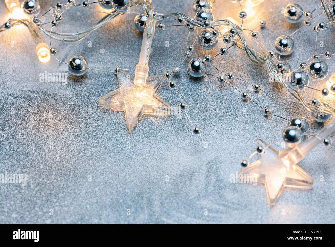 silver christmas background with glowing light garlands and decorative beads. macro view Stock Photo