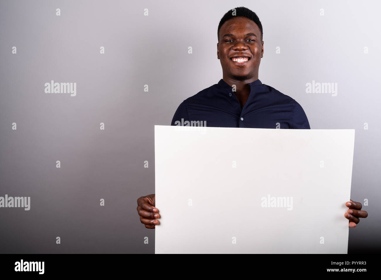 Young African businessman holding white board against white back Stock Photo