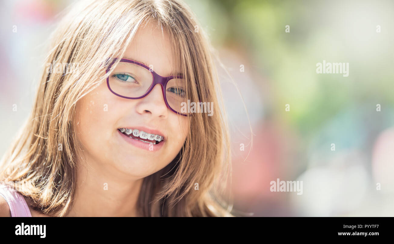 Happy smiling girl with dental braces and glasses. Young cute caucasian