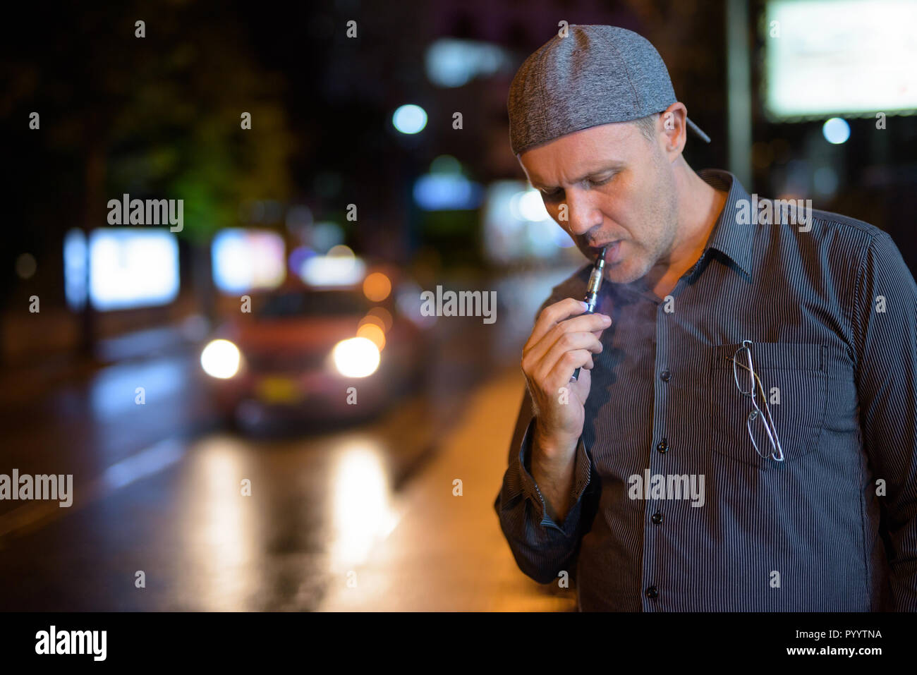 Mature man smoking electronic cigarette in the streets at night Stock Photo