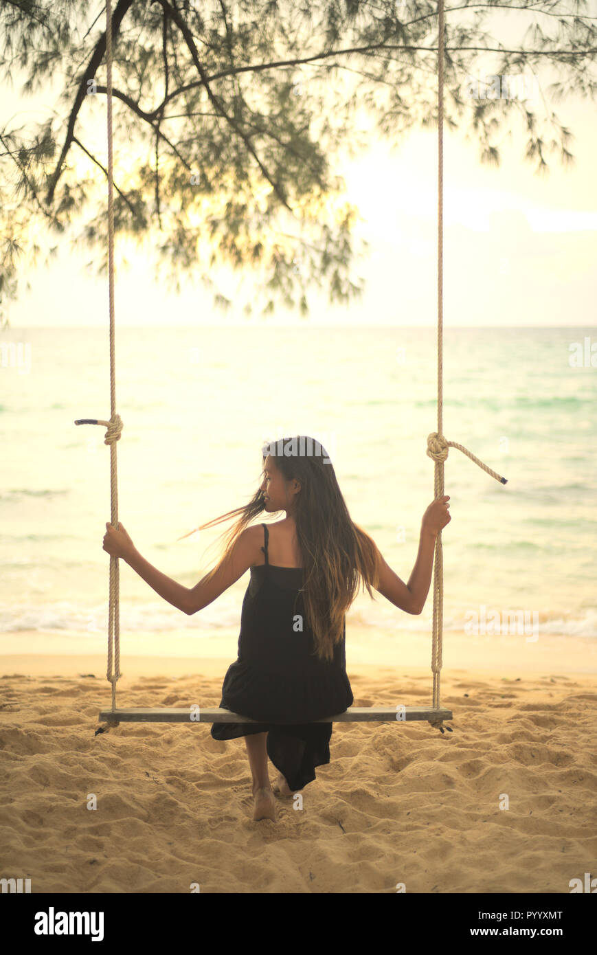 A young asian Vietnamese woman sitting on a swing on the beach posing with  sky and sea in background Stock Photo - Alamy