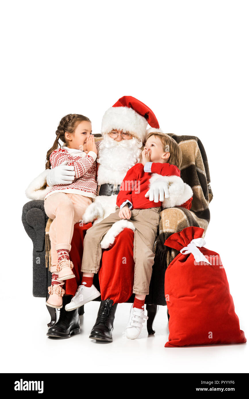 kids whispering to santa while thay sitting in armchair together isolated on white Stock Photo