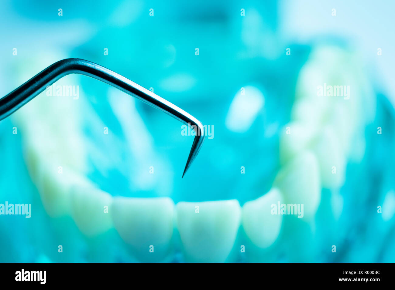 Dentist cleaning teeth with titanium metal tooth pick instrument to