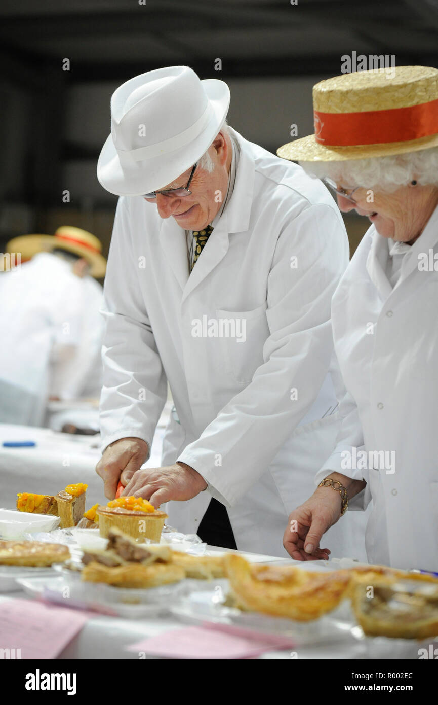 A pair of judges examine pies and other meat produce at a regional competition for producers. Stock Photo
