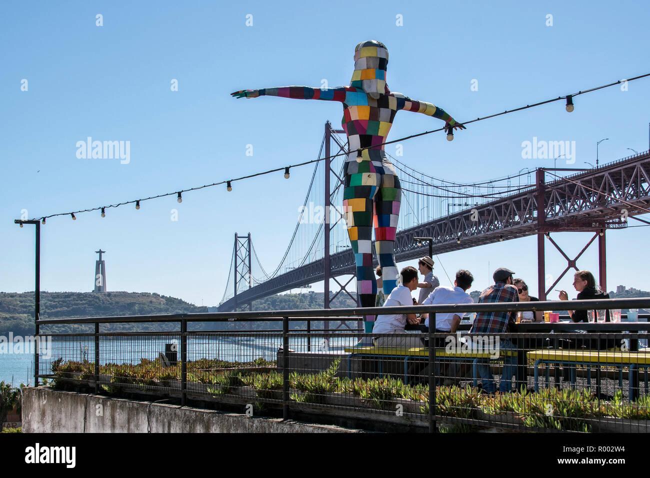 Rooftop bar with statue at LX Factory, under the Ponte 25 de Abril