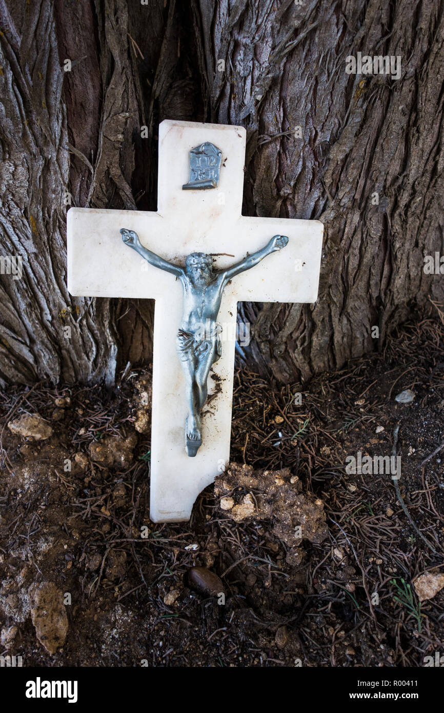 marble cross with crucified jesus christ against old tree Stock Photo