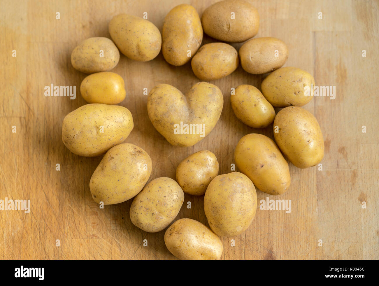 potatoes on wooden board, one of them in the shape of a heart Stock Photo