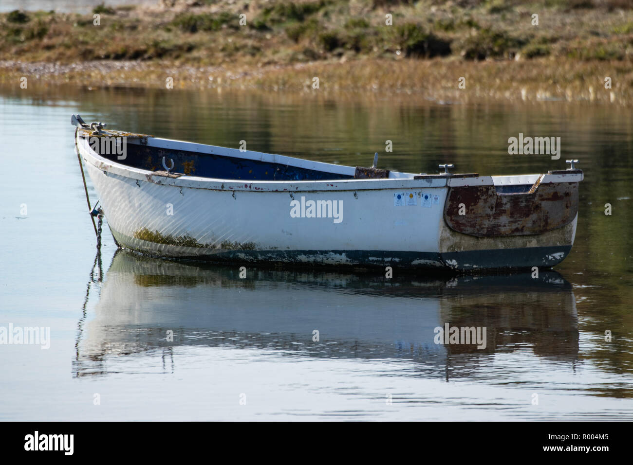 A Single old wooden boat reflecting on very calm waters Stock Photo
