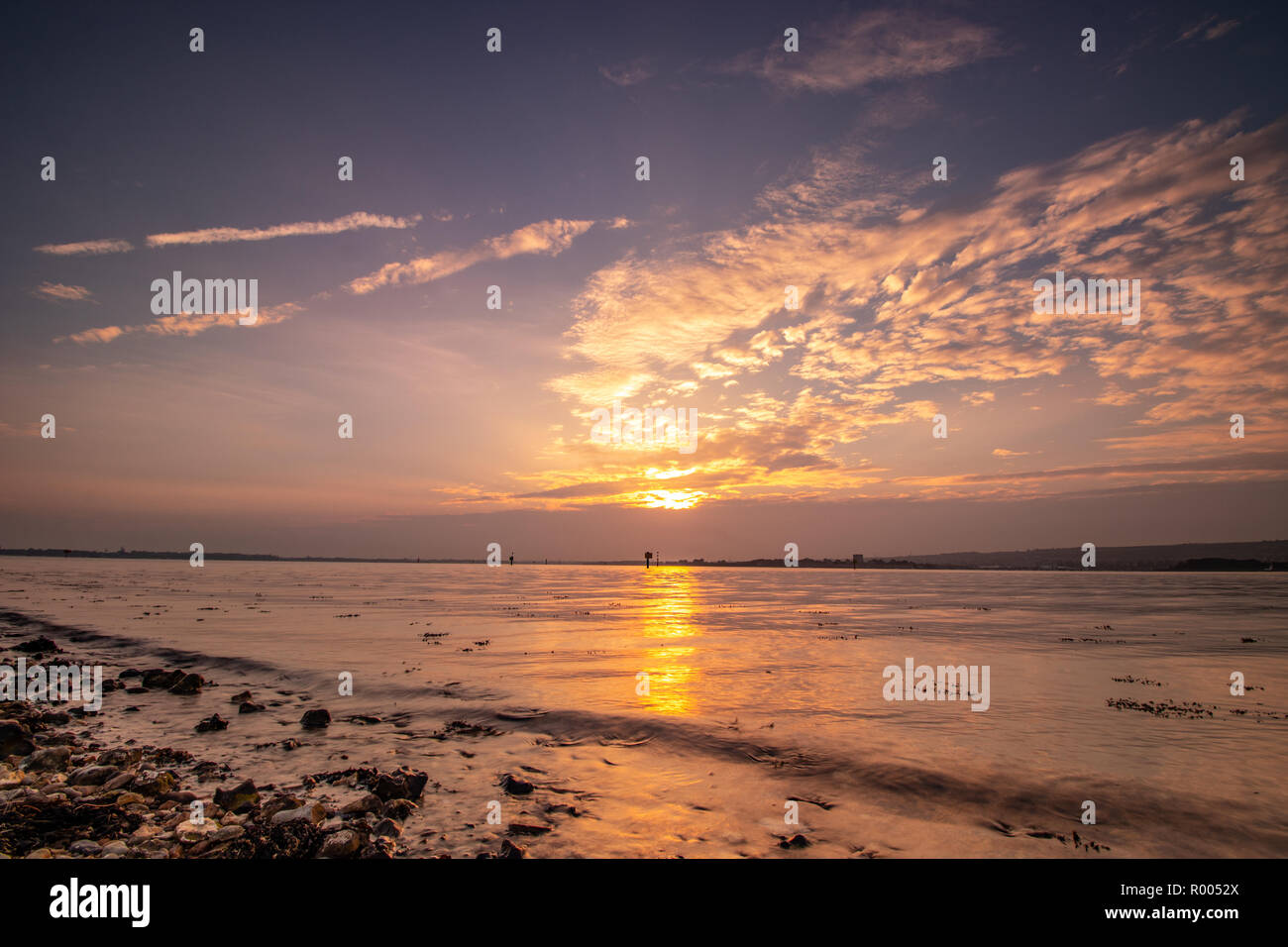light rays through clouds at sunset on the shoreline Stock Photo