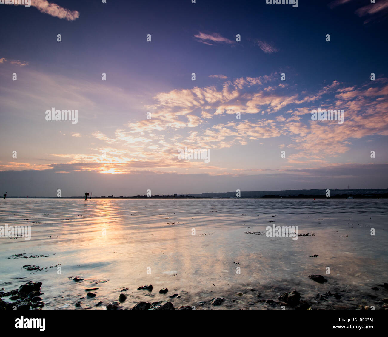 light rays through clouds at sunset on the shoreline Stock Photo