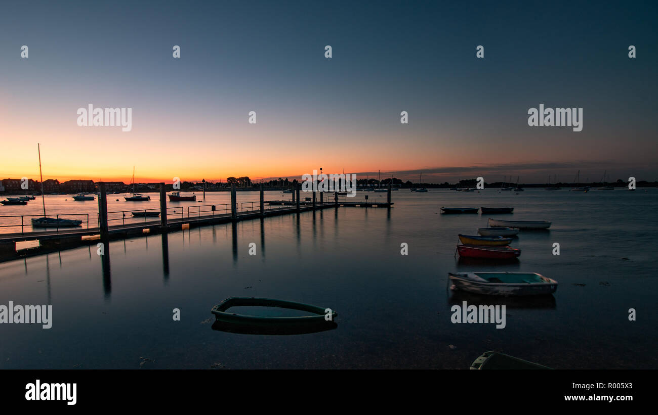 boats on calm waters next to a wooden jetty just before sunrise Stock ...