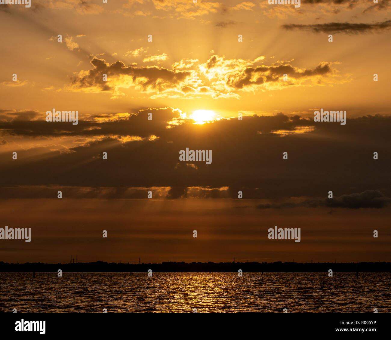 light rays shining through clouds at the coastline Stock Photo