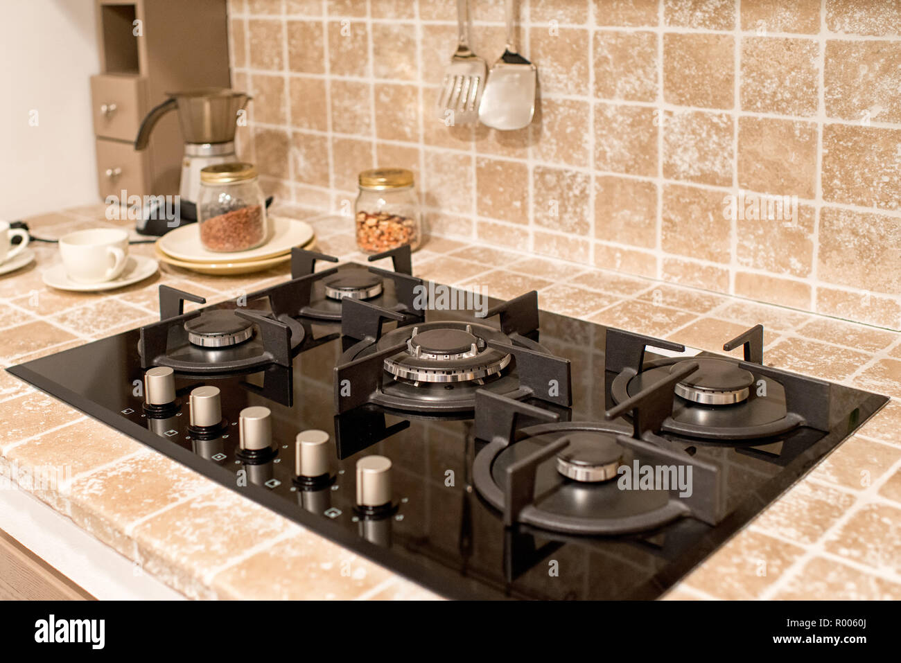 Fitted gas burner with five hotplates in a tiled kitchen counter with splash back in a close up view Stock Photo