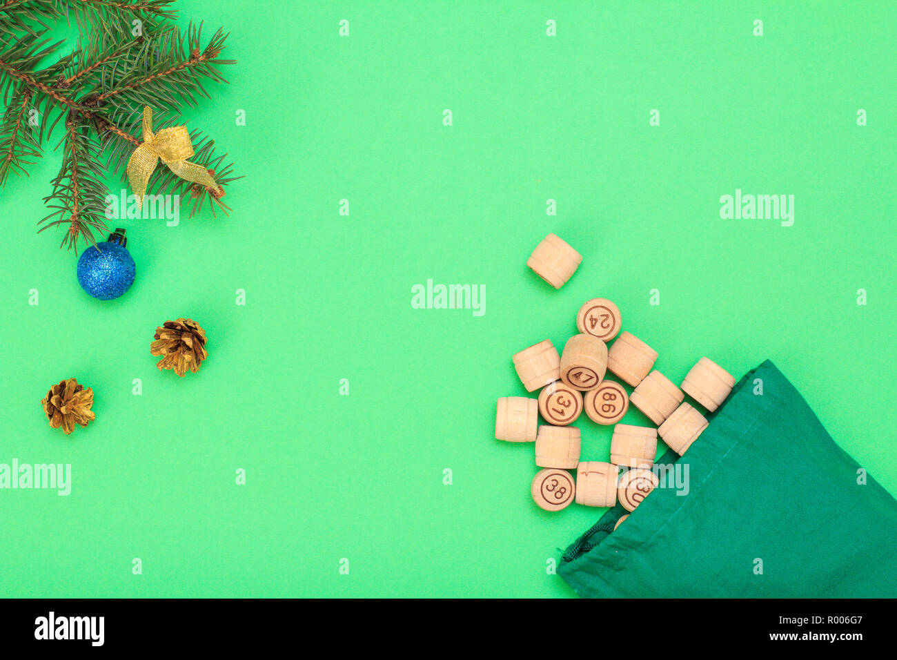 Board game lotto. Wooden lotto barrels with bag, Christmas fir tree branches, cones and toy ball on green background. Top view Stock Photo