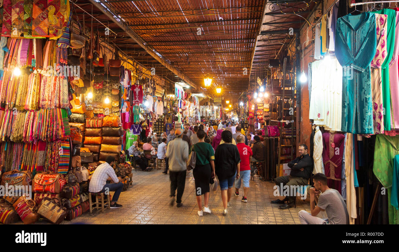 MARRAKESH, MOROCCO - APR 28, 2016: Tourists and local people walking through the shopping souks in the old medina of Marrakech. Stock Photo