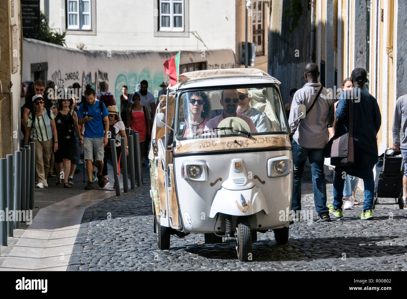 Tourists being driven through the narrow streets of the Alfama district in a rickshaw, tuk tuk,  Lisbon, Portugal. Stock Photo