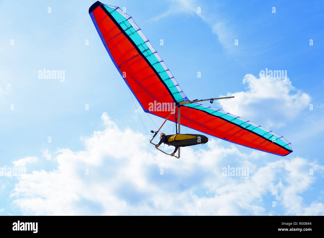 The hang glider on a red hang-glider is flying in a blue sky Stock Photo