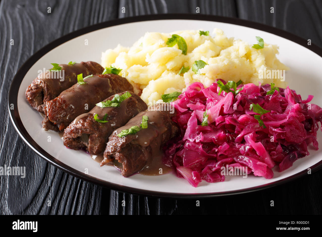 Beef rolls with mustard, bacon and pickles on a plate served with mashed potatoes and red cabbage close-up. horizontal Stock Photo