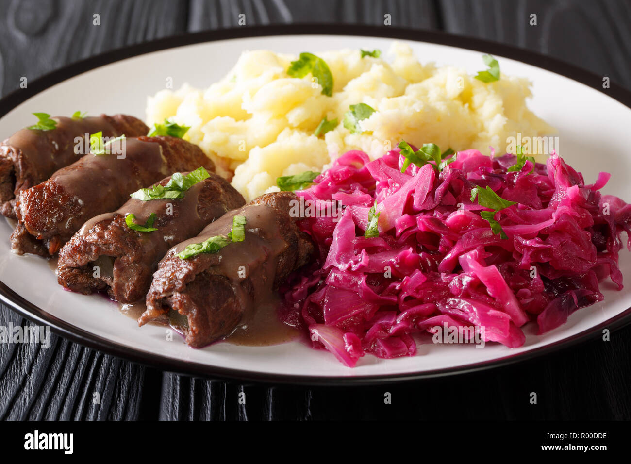 German beef rouladen recipe, along with mashed potato and red cabbage close-up on a plate. horizontal Stock Photo