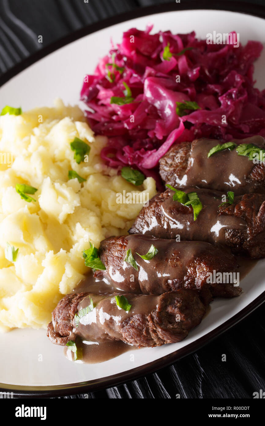 Traditional German Beef Rouladen with a wonderful gravy served with mashed potatoes and red cabbage close-up on a plate. vertical Stock Photo