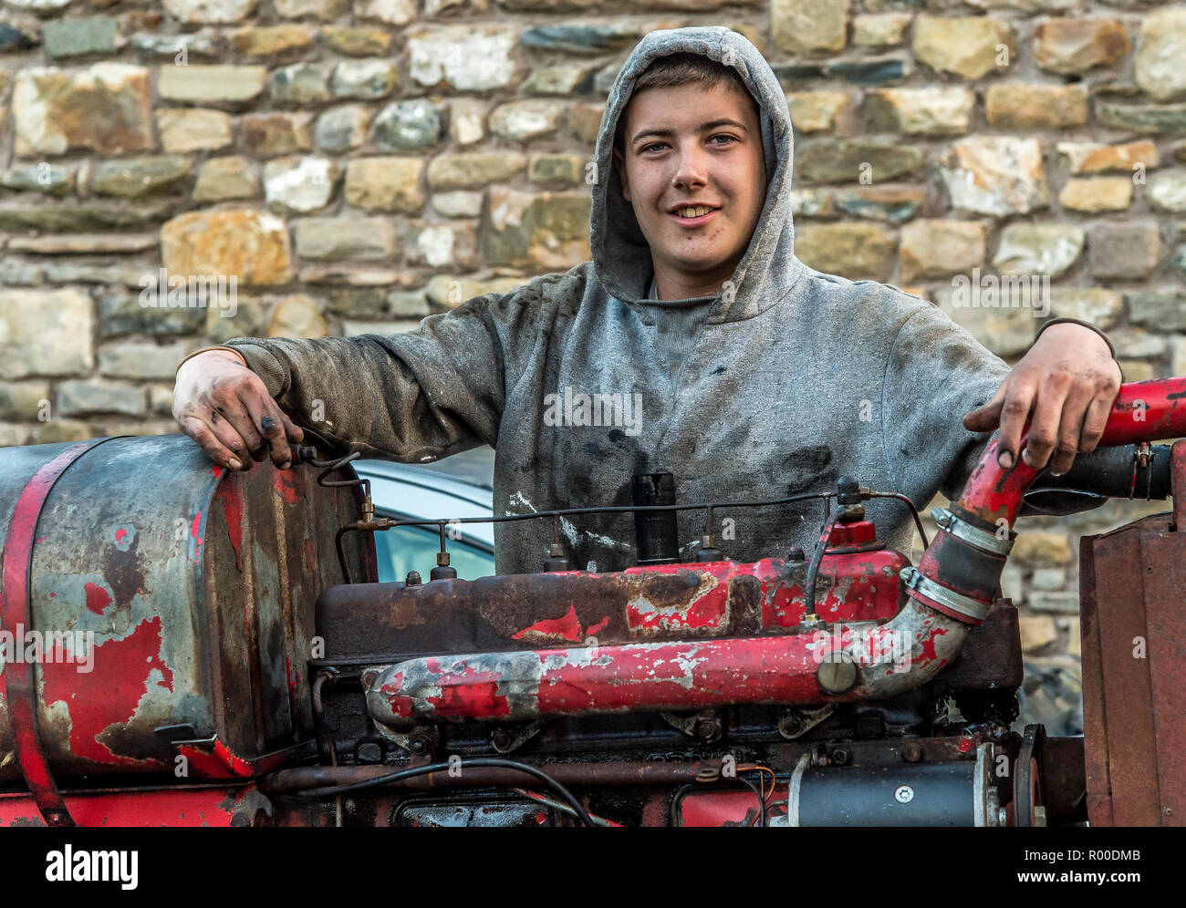 Young apprentice heavy goods mechanic posing by a tractor engine Stock Photo