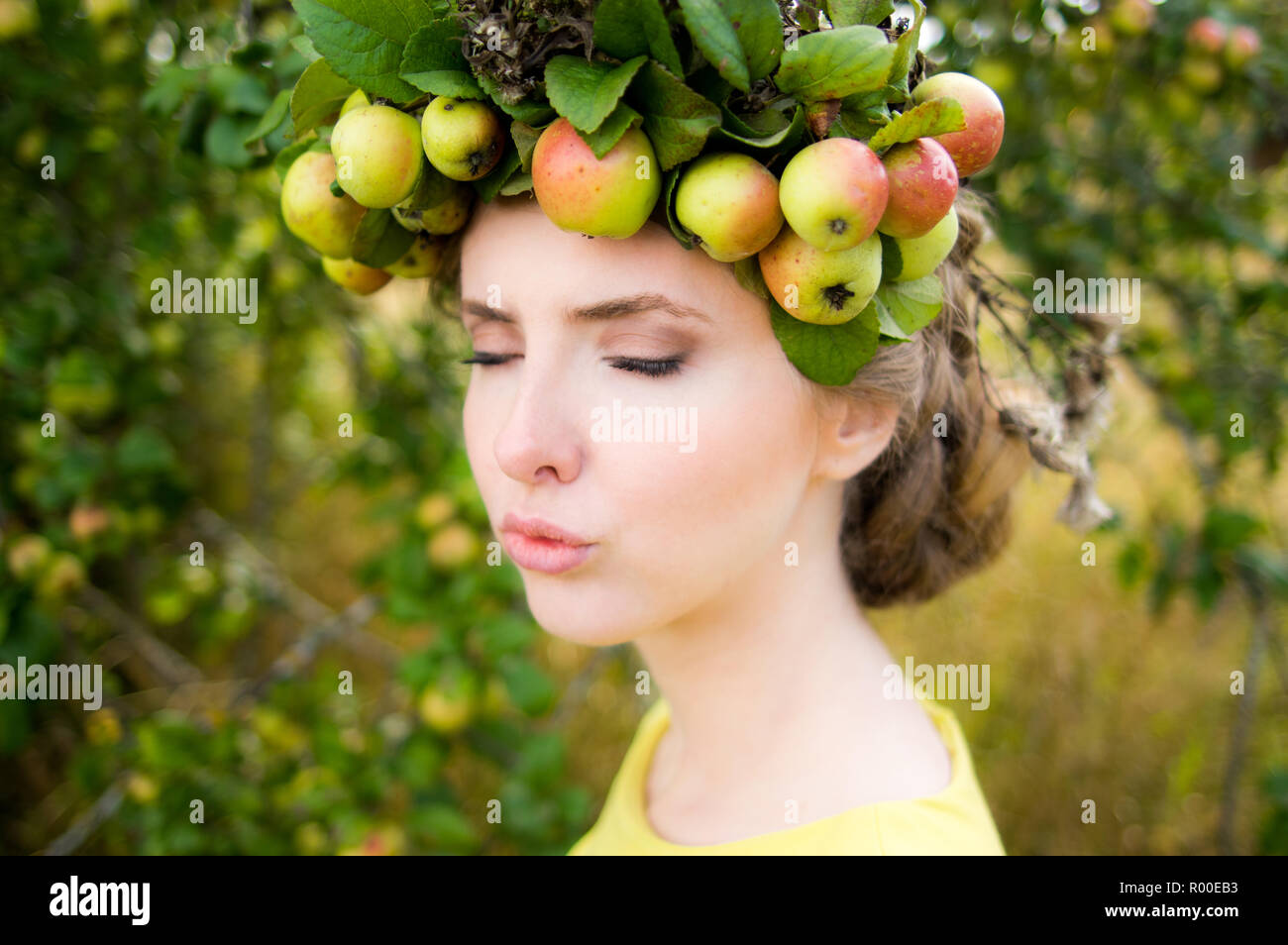 Young woman with wreath on the head from apples and closed eyes making
