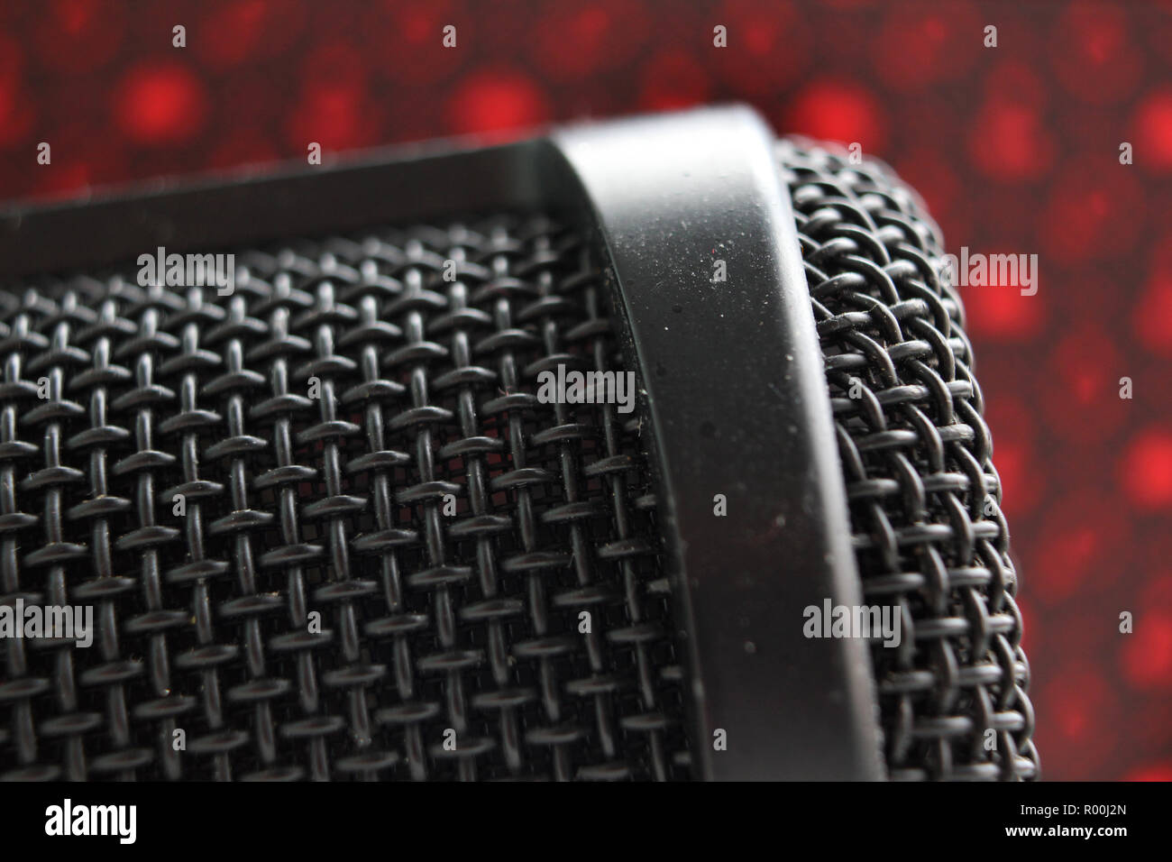 Condenser Microphone grill with red background, close up Stock Photo
