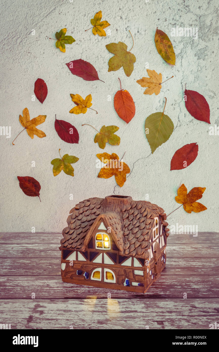 Autumn concept - miniature house with colourful autumn leaves / foliage in the background - autumnal scene Stock Photo