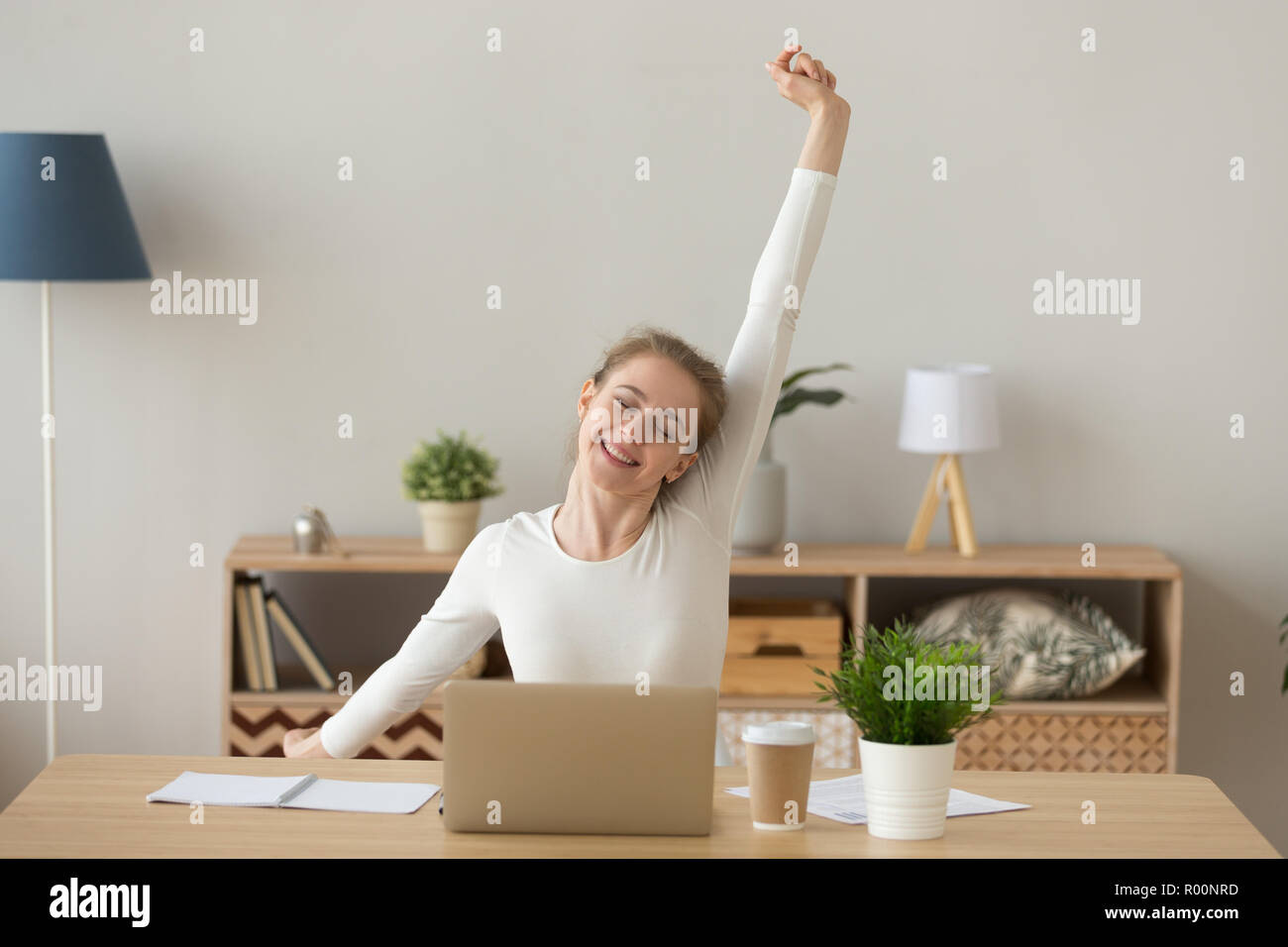 Satisfied girl sitting at the desk relaxing in office Stock Photo