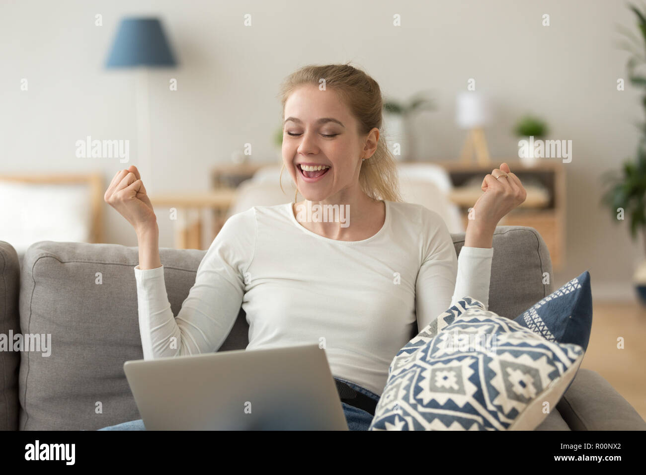 Happy laughing woman sitting on couch with laptop Stock Photo - Alamy
